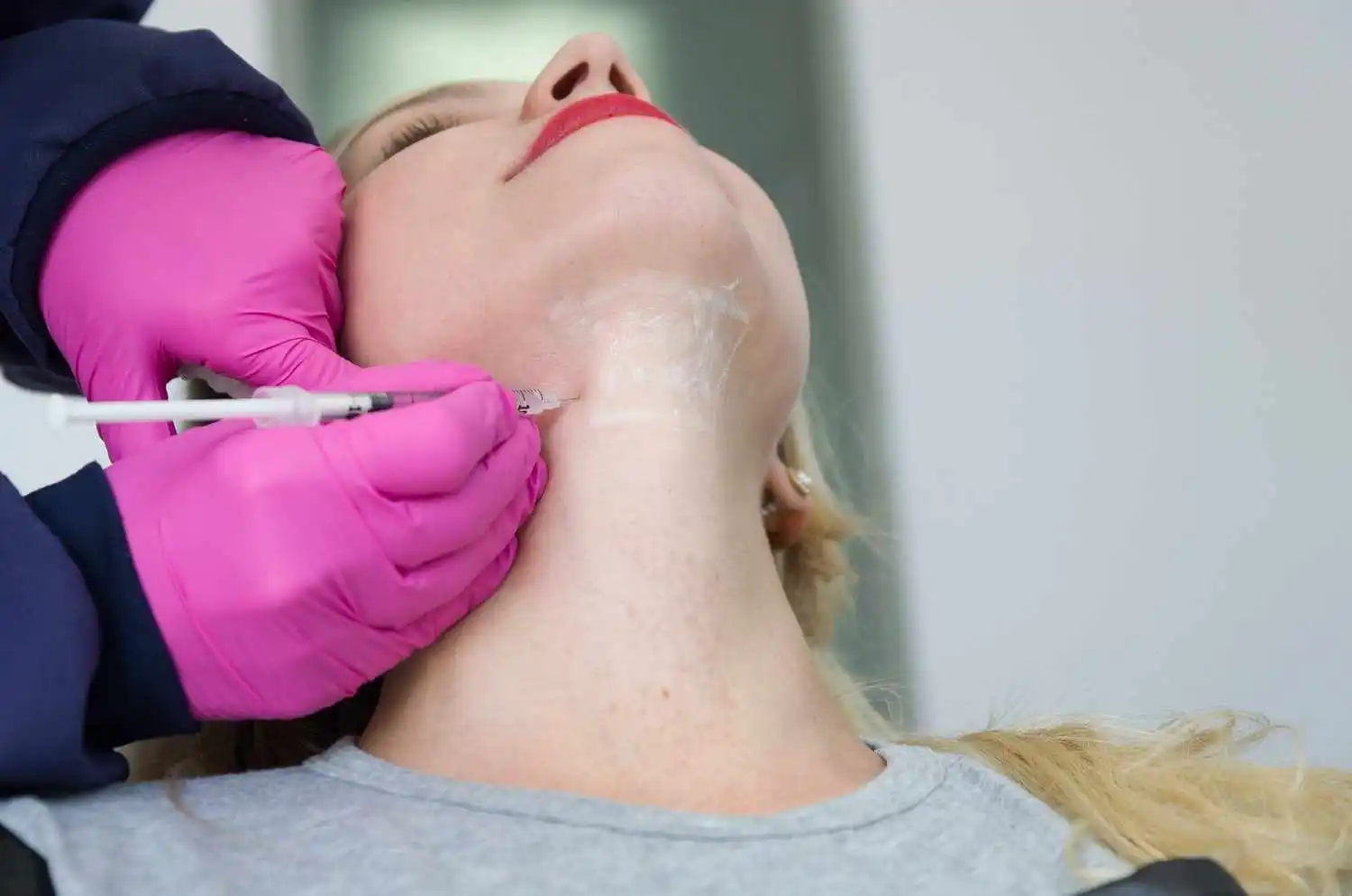 Woman receiving a Kybella injection under the chin for double chin fat reduction
